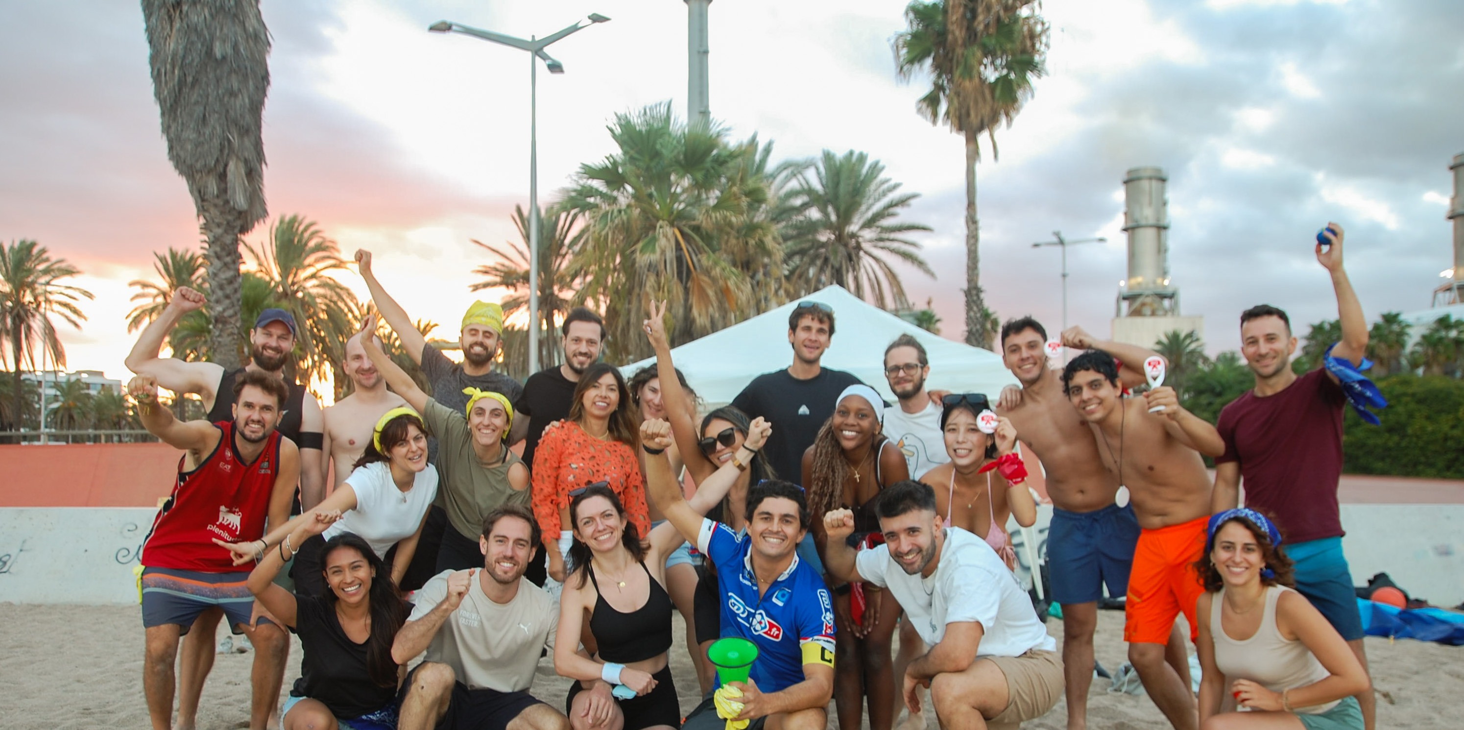A Barcelona Games crew of around 20 people celebrating together on the beach at sunset